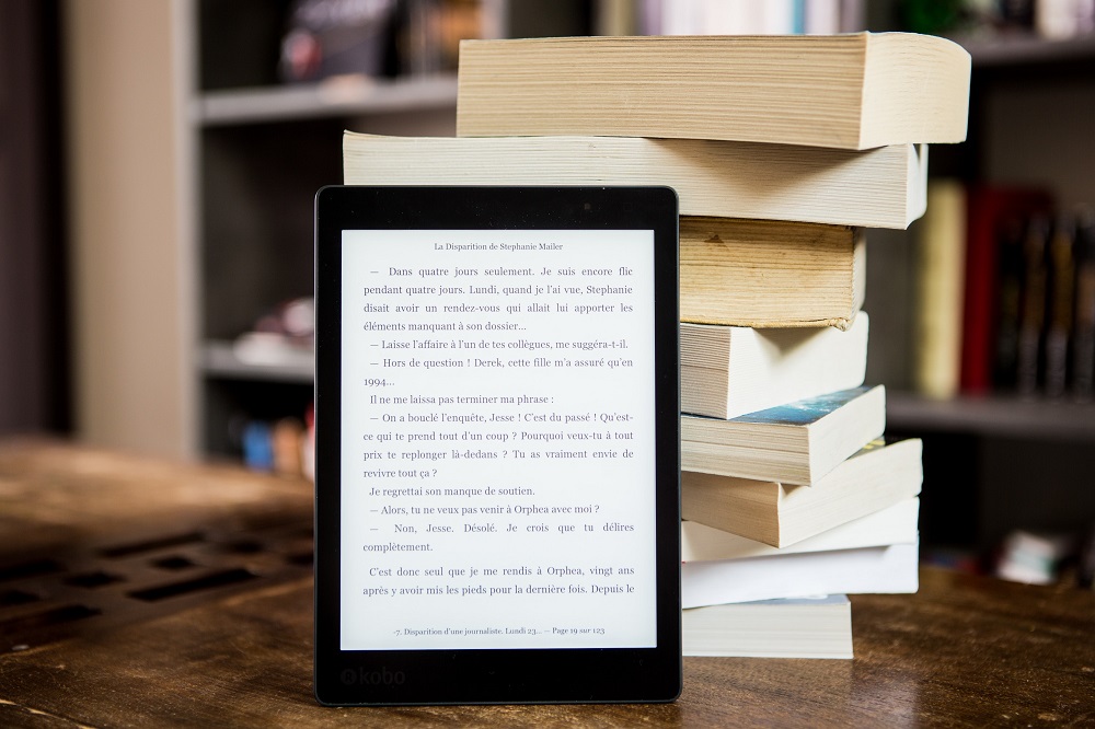 a picture of an e-book next to a stack of physical books.